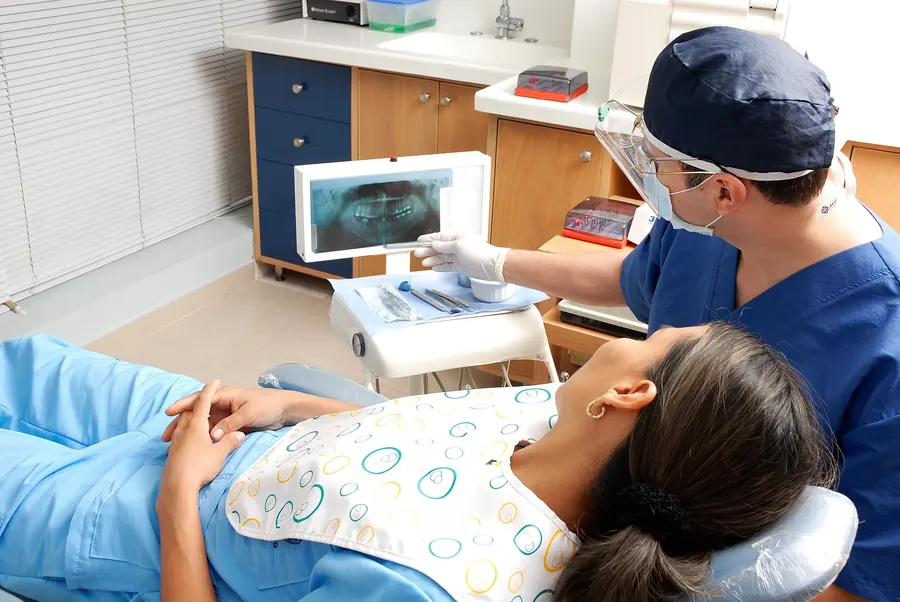 Dentist pointing at an X-ray while a patient lies in the chair